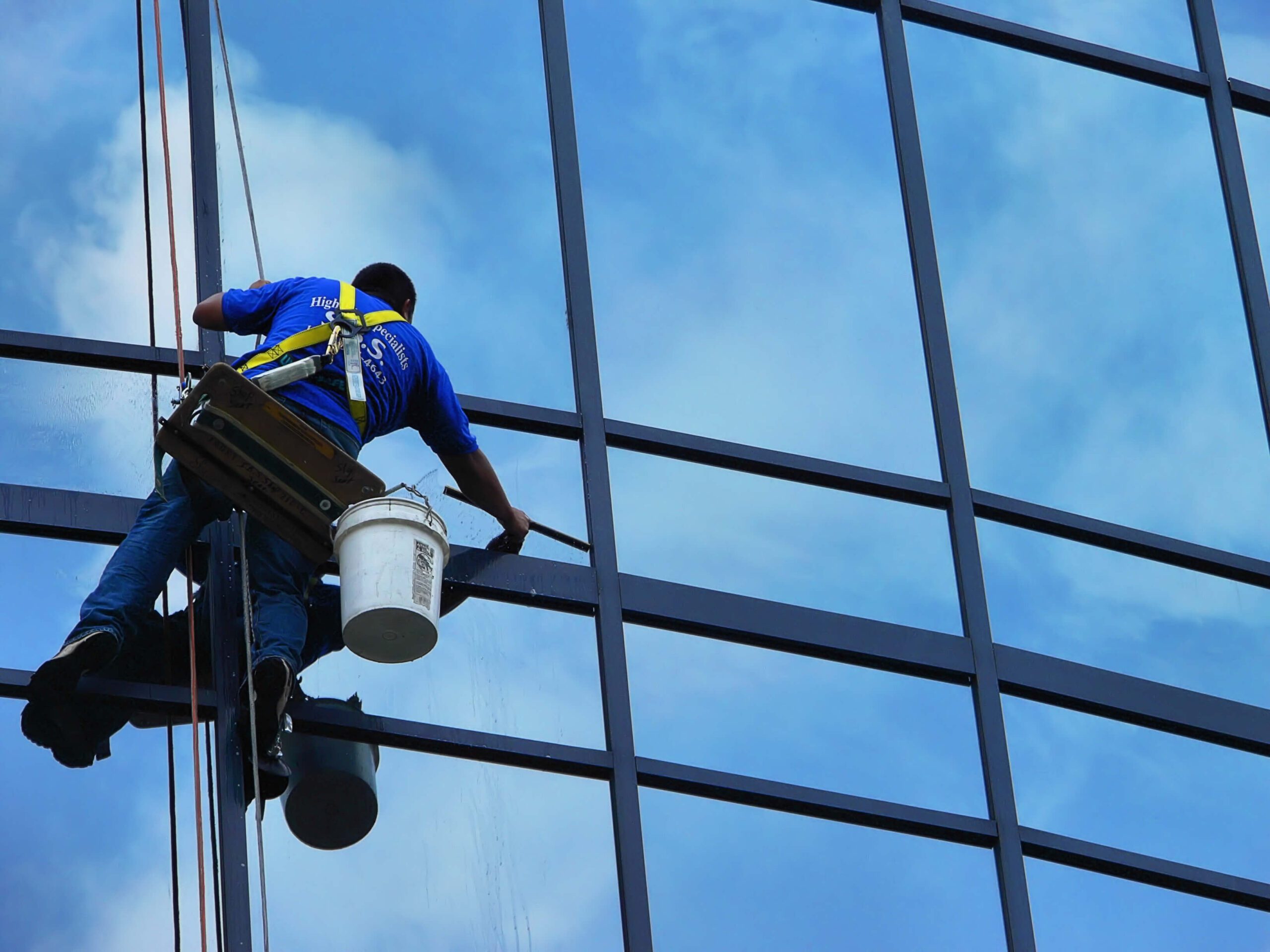 A cleaner washing windows on a commercial high-rise building.