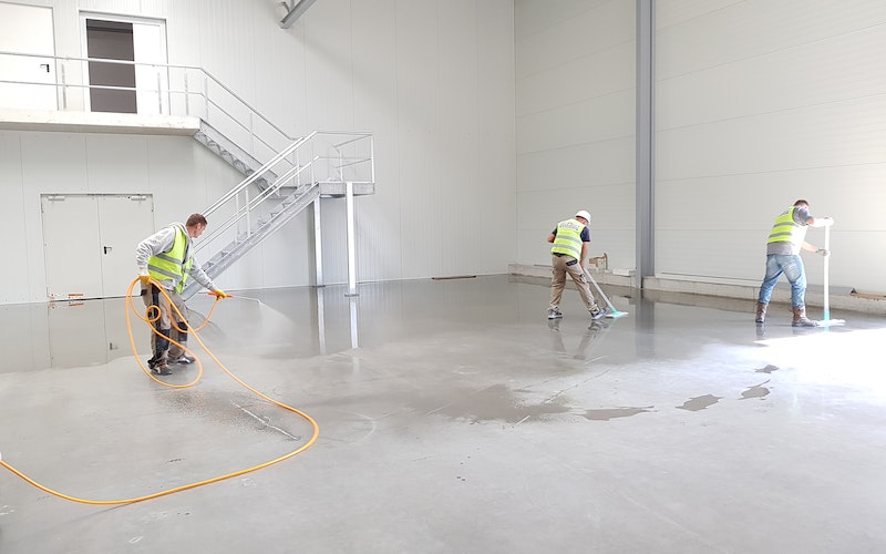 Construction workers and cleaning crew working in a warehouse.