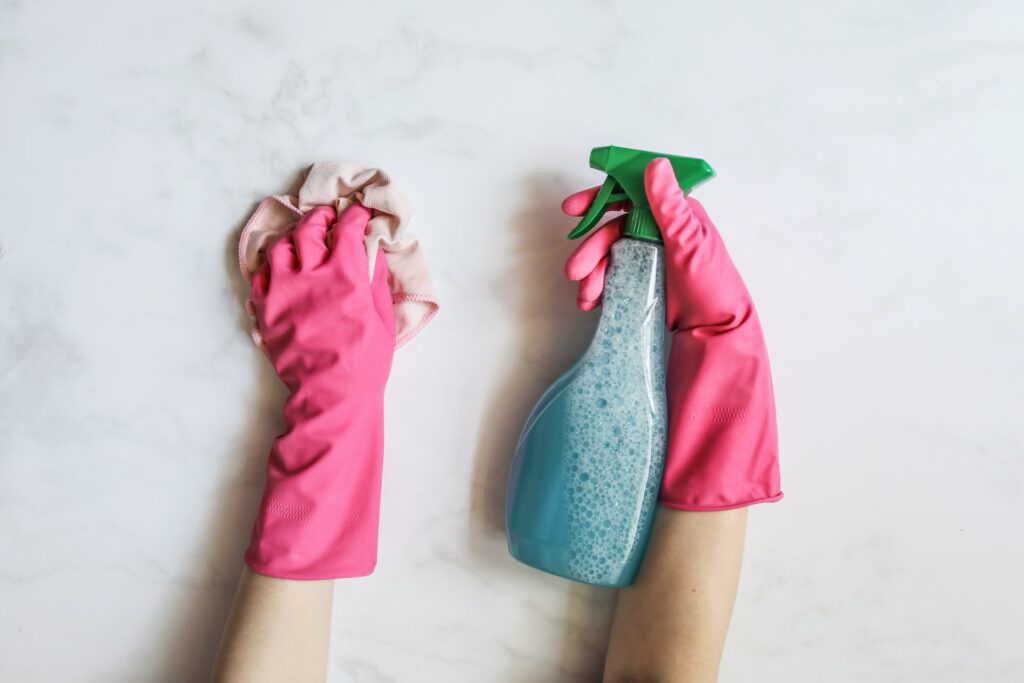 Gloved hands holding cleaning products