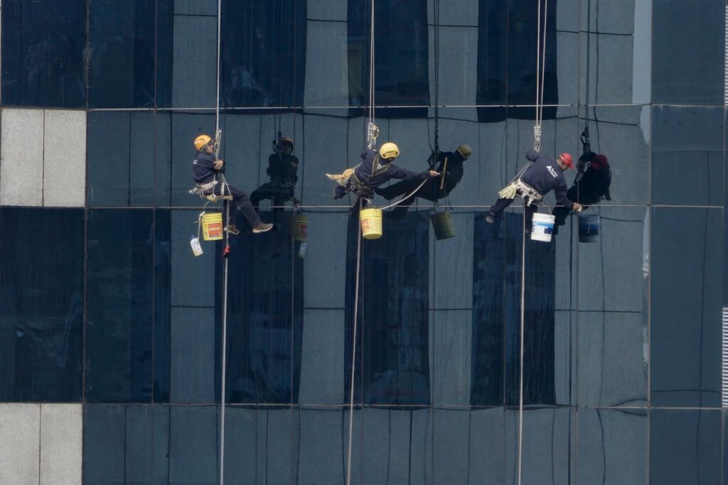 Professionals on a harness cleaning windows