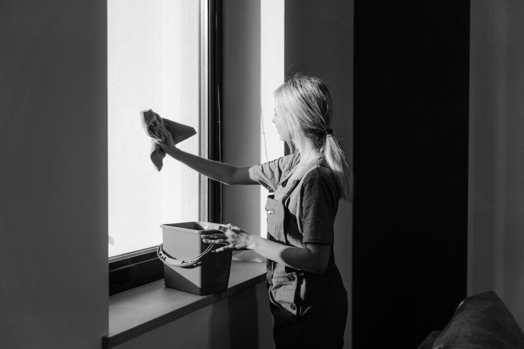 Woman cleaning a window while smiling