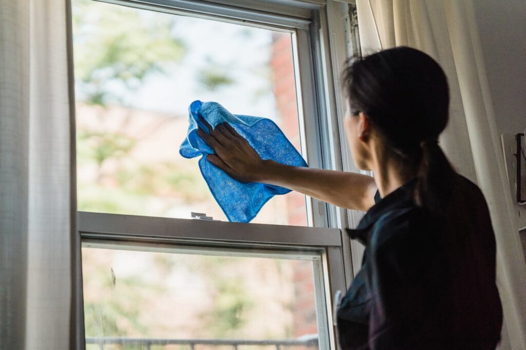 a woman cleaning window with microfiber cloth